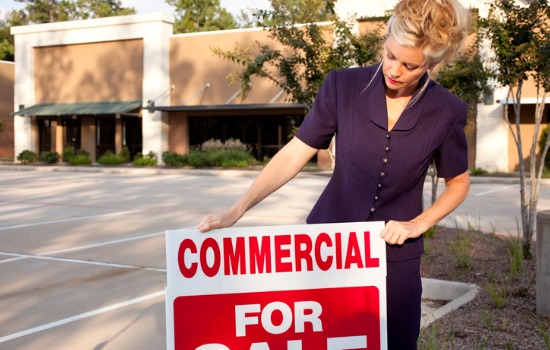 A real estate agent placing a for sale sign in front of a commercial property, an extension of Real Estate Law in Kiawah Island SC