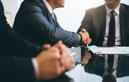 A corporate attorney shaking hands with a client at a conference table